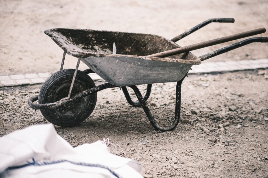 A wheelbarrow filled with soil and plants. It represents the importance of wheelbarrows in gardening and planting tasks. The wheelbarrow has a single wheel at the front, a shallow tray, and handles for maneuvering. It showcases the versatility and efficiency of using a wheelbarrow for transporting heavy loads and enhancing productivity in the garden.